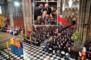 A large gathering inside a cathedral with a checkered floor, ornate decorations, and people in formal attire. A casket draped with a flag is positioned near the altar. An inset close-up shows a group of people in conversation among the attendees.