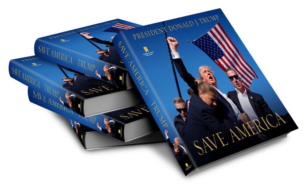 Stack of books titled "Save America" by President Donald J. Trump, featuring a cover image of Trump with people and an American flag in the background, published by Winning Team Publishing.