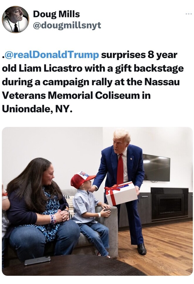 Doug Mills tweet of Donald Trump surprising 8-year-old Liam Licastro with a gift backstage during a campaign rally at Nassau Veterans Memorial Coliseum in Uniondale, NY. Trump is wearing a blue suit and red tie, while Liam is sitting on a couch with his mother, wearing a red baseball cap and blue shirt.