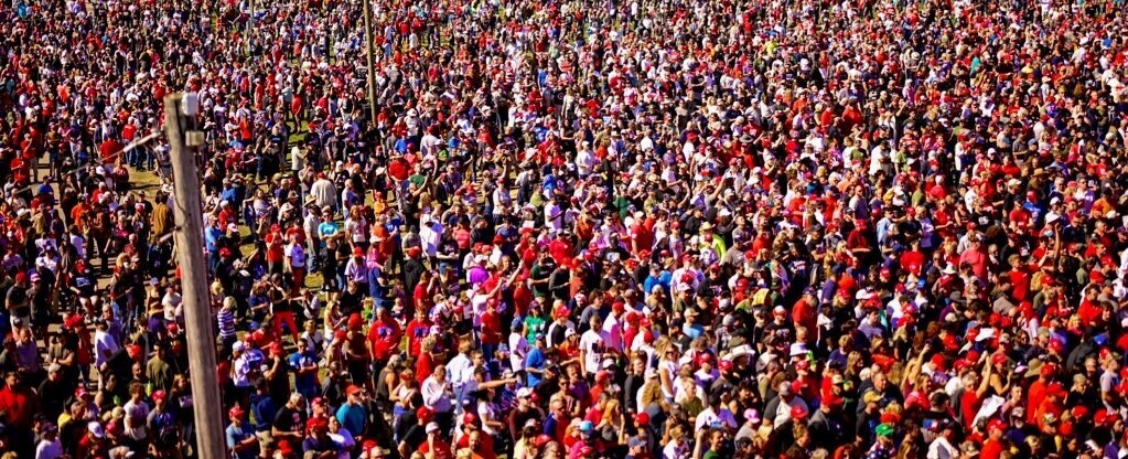 A large crowd of people, many wearing red, gathered closely together outdoors, indicating a large public event or rally.