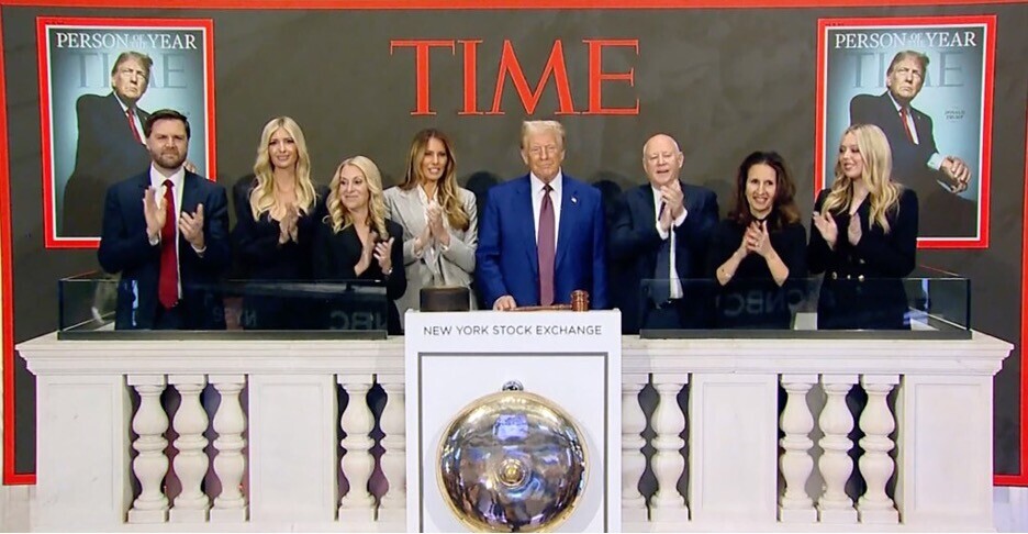 Group of people, including a prominent figure, standing at the New York Stock Exchange podium clapping. TIME magazine covers featuring the prominent figure as Person of the Year displayed in the background.